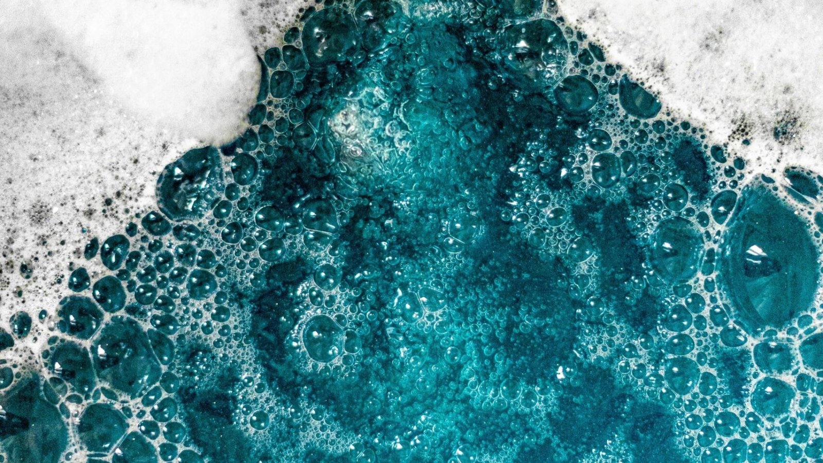 Close-up of blue foam bubbles merging with water, creating a mesmerizing texture.