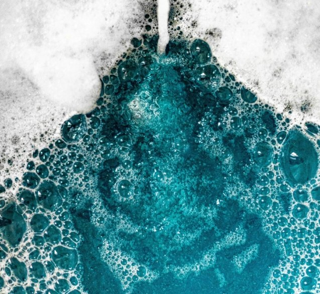 Close-up of blue foam bubbles merging with water, creating a mesmerizing texture.